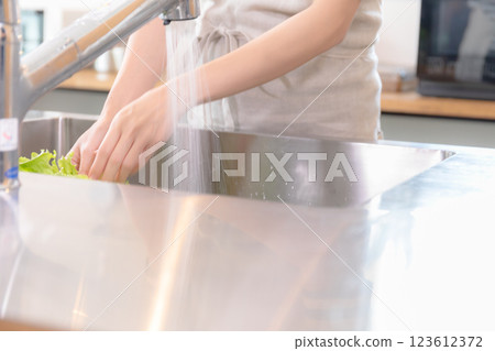 A young lady washing vegetables in the kitchen A young lady washing vegetables in the kitchen 123612372