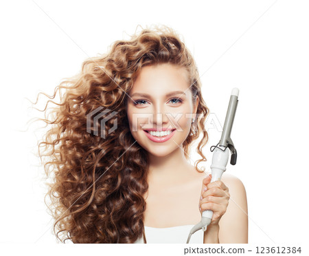 Joyful woman with curly hairstyle using hot curling tongs iron, indoor fashion portrait. Joyful woman with curly hairstyle using hot curling tongs iron, indoor fashion portrait. 123612384