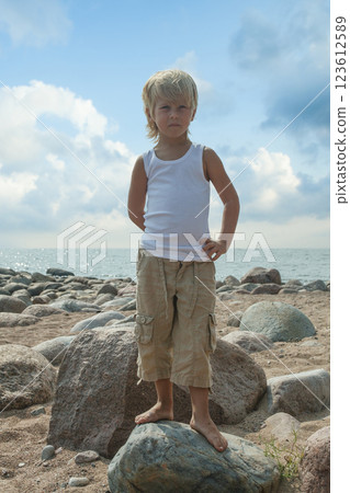 Young child boy in white t-shirt on the sand beach, fashion portrait Young child boy in white t-shirt on the sand beach, fashion portrait 123612589