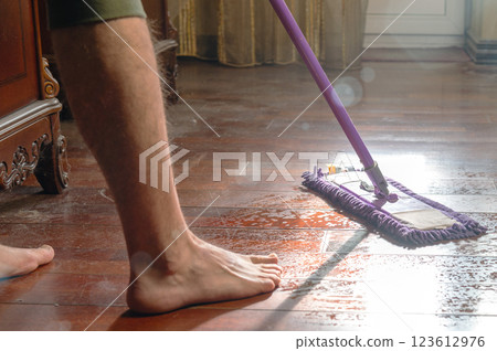 Man mops a dirty wooden floor. Man doing housework at home. Mopping the floor Man mops a dirty wooden floor. Man doing housework at home. Mopping the floor 123612976