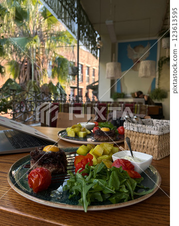 Gourmet beef dish with egg yolk, caramelized onions, roasted potatoes, tomatoes, arugula, and sauce in a stylish cafe. Suitable for food photography and restaurant menus. Gourmet beef dish with egg yolk, caramelized onions, roasted potatoes, tomatoes, arugula, and sauce in a stylish cafe. Suitable for food photography and restaurant menus. 123613595