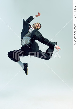 Young businessman extending leg high with sharp motion and serious gaze against white studio background. 123614276