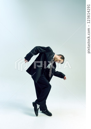 Businessman bending forward, arms loosely hanging, head tilted in deep thought against white studio background. Concept of business, mental fatigue 123614291