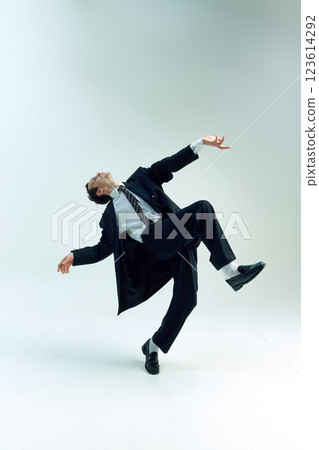 Young businessman dynamically balancing mid-motion, arms spread, body arched against white studio background. Concept of business, emotions Young businessman dynamically balancing mid-motion, arms spread, body arched against white studio background. Concept of business, emotions 123614292