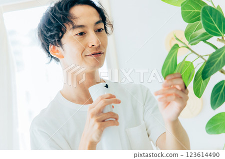 一個男人給觀葉植物澆水 123614490