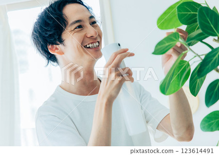 一個男人給觀葉植物澆水 123614491