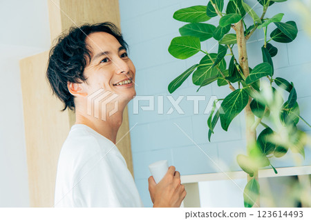 一個男人給觀葉植物澆水 123614493