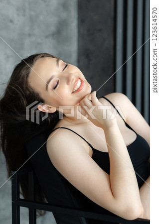 Young woman relaxing on a modern black armchair in a minimalist interior Young woman relaxing on a modern black armchair in a minimalist interior 123614570