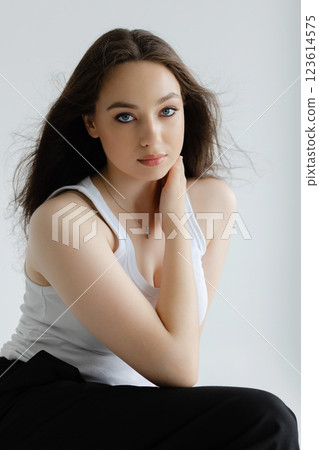 Young woman sitting on stool posing in studio with white background Young woman sitting on stool posing in studio with white background 123614575