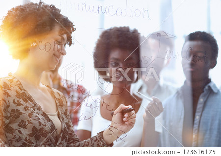 a team of young designers sticking notes on glass in a modern office a team of young designers sticking notes on glass in a modern office 123616175