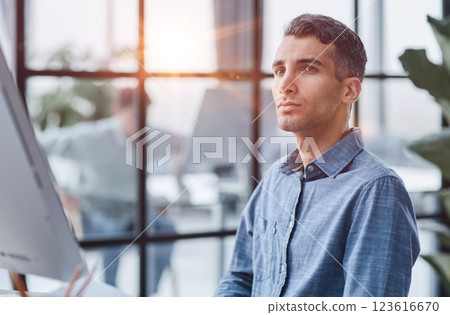 A young pensive man works in the office and thinks about something. A young pensive man works in the office and thinks about something. 123616670