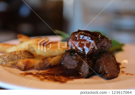 pour sauce over meat medium grill barbecue cook pours sauce over cooked beef steak, close-up 123617064
