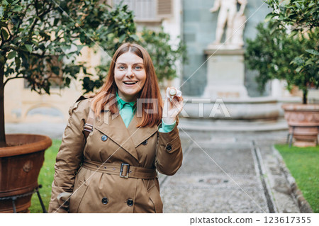Happy 30s woman holding Sicilian cannolo tube pastry filled with cream outdoors. Travel, Italy, food and holidays concept. Young woman eating traditional delicious cake cannoli, Traveling Europe Happy 30s woman holding Sicilian cannolo tube pastry filled with cream outdoors. Travel, Italy, food and holidays concept. Young woman eating traditional delicious cake cannoli, Traveling Europe 123617355