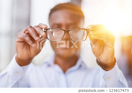 a black man in a blue shirt adjusts his glasses. a black man in a blue shirt adjusts his glasses. 123617473