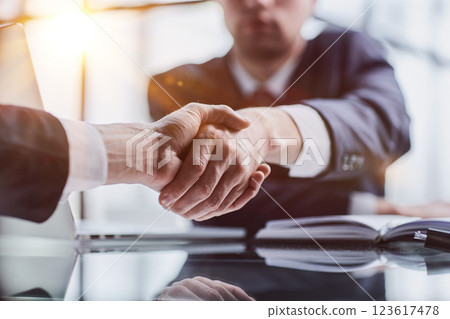 Close-up high-angle view of unrecognizable business men handshaking after close deal and signed agreement at office over table paper contract. 123617478