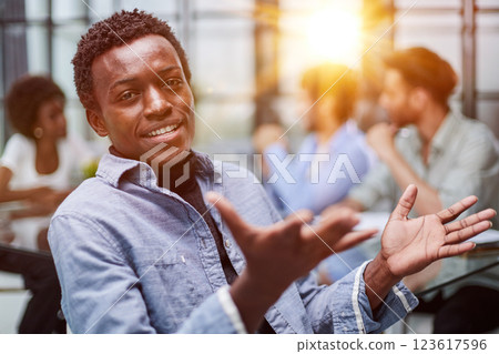 smiling African American business man with executives working in background smiling African American business man with executives working in background 123617596