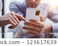 colleague at work points to a file in a partner's smartphone 123617639