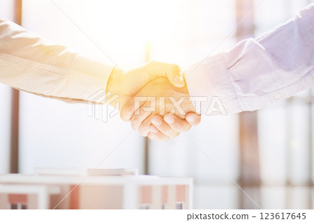 handshake against the background of a model of a house under construction. client and designer 123617645