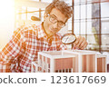 the guy looks at the layout of the house through a magnifying glass 123617669