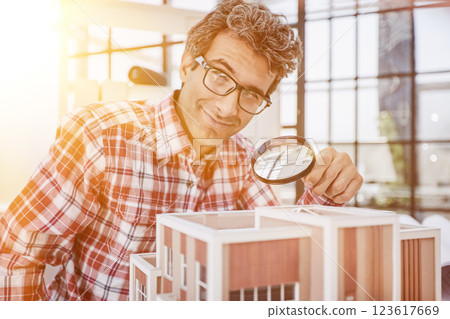 the guy looks at the layout of the house through a magnifying glass 123617669
