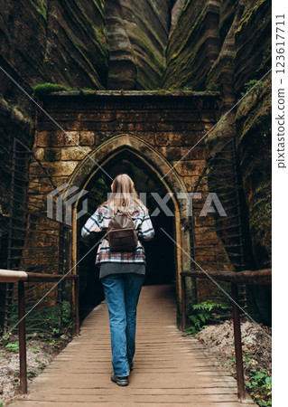 A tourist woman with a backpack stands against the background of a rocks. Young 30s blonde woman hiking in nature. Concept of an active lifestyle. High quality photo. Full body, rear view A tourist woman with a backpack stands against the background of a rocks. Young 30s blonde woman hiking in nature. Concept of an active lifestyle. High quality photo. Full body, rear view 123617711