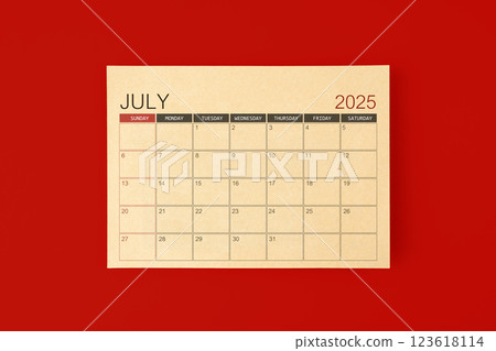 July 2025 desk calendar made from brown paper page on red background. 123618114