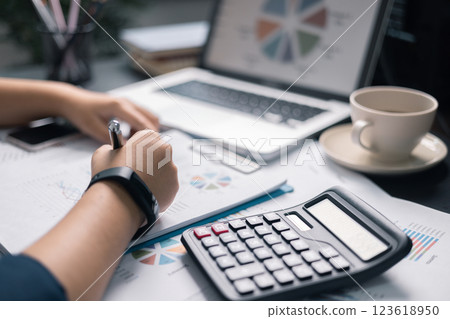 Finance bank tax expense accounting budget money businessman hand use calculator Financial calculate accountant close up calculator with graph chart write office desk Business expense analysis saving 123618950