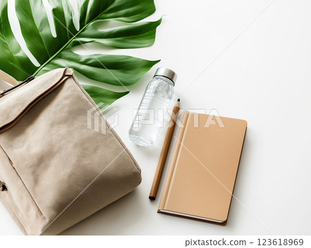 A minimalist flat lay of a beige backpack, notebook, pencil, and reusable water bottle A minimalist flat lay of a beige backpack, notebook, pencil, and reusable water bottle 123618969