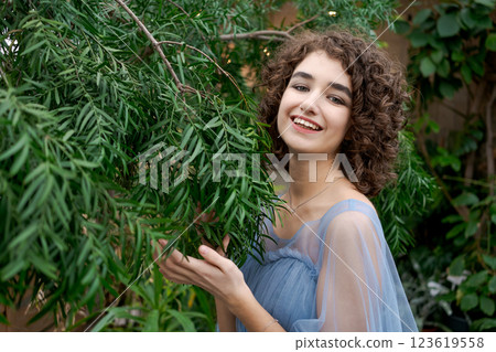 Woman with curly hair is standing in front of a tree 123619558