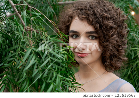 Woman with brown hair is standing in front of a tree Woman with brown hair is standing in front of a tree 123619562