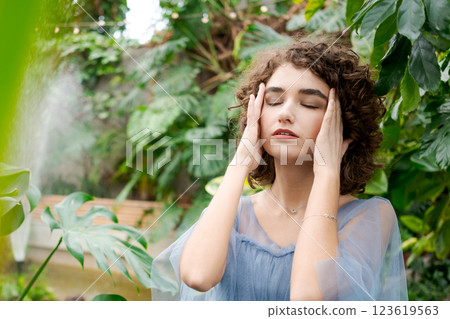 Woman with brown hair is sitting on a bench in a park Woman with brown hair is sitting on a bench in a park 123619563