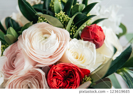 Women's Day greeting card. delicate bouquet featuring white, pink, and red ranunculus flowers, accented with lush greenery, creating a soft and romantic floral arrangement. 123619685