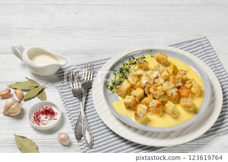 pollock cubes poached in cream saffron sauce 123619764