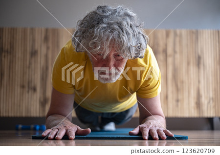 Senior man holding a plank pose exercise on a yoga mat Senior man holding a plank pose exercise on a yoga mat 123620709