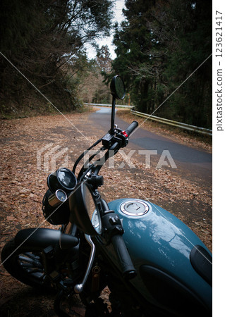 一輛摩托車駛向山區的森林公路 一輛摩托車駛向山區的森林公路 123621417