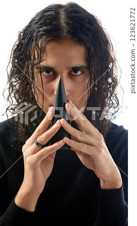 Young man in black turtleneck holding stylish black skincare bottle with confident expression against white studio background. 123621772