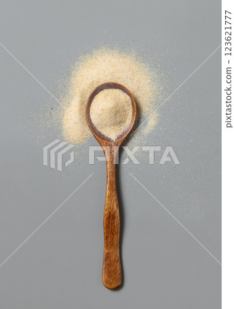 Wooden spoon full of beige powder on grey top view. Dietary supplement or kitchen spice Wooden spoon full of beige powder on grey top view. Dietary supplement or kitchen spice 123621777