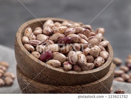 Wooden bowl full of dried raw pinto beans on gray closeup. Traditional Latin American legumes Wooden bowl full of dried raw pinto beans on gray closeup. Traditional Latin American legumes 123621782