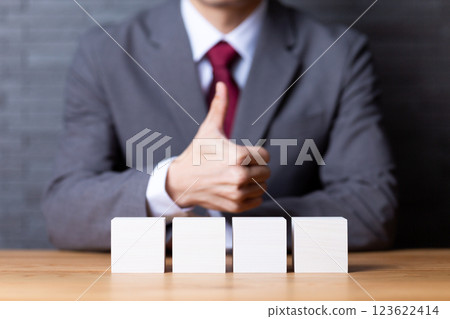 四塊白色木塊和一位豎起大拇指的中年男性商人 123622414