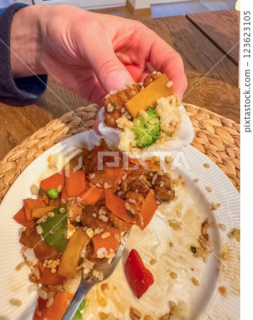 male eating stir-fry with vegetables and rice,holding bite-sized portion in hand. High quality photo 123623105