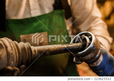 Close-up of a Mechanic Reassembling a Car's Drive Shaft Joint in a Workshop 123623522
