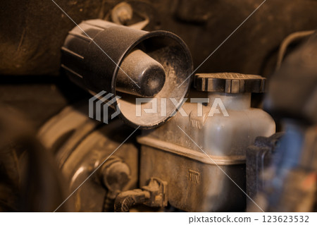 Close-up Detailed View of Dusty Vehicle Brake Fluid Reservoir and Cap Under Car Hood 123623532