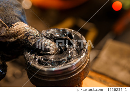 Close-Up of Worker Applying Grease Lubricant to Mechanical Part with Finger While Wearing a Protective Glove 123623541