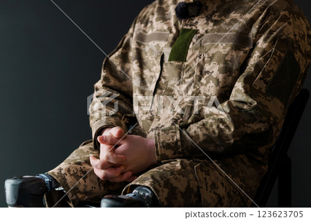 A Soldier in Military Uniform with Advanced Bionic Leg Prosthesis Sitting Thoughtfully 123623705