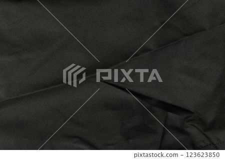 Close-up view of textured black fabric with subtle folds and wrinkles under soft lighting Close-up view of textured black fabric with subtle folds and wrinkles under soft lighting 123623850