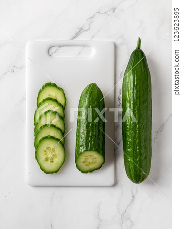 Raw green cucumbers on a white cutting board. 123623895