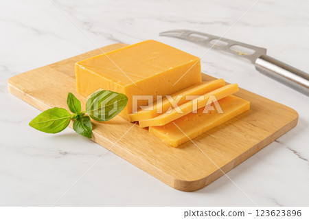 Sheddar cheese slices on a cutting board. Sheddar cheese slices on a cutting board. 123623896
