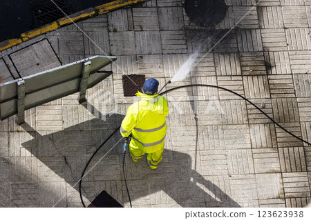 Worker cleaning a street sidewalk with high pressure water jet machine 123623938
