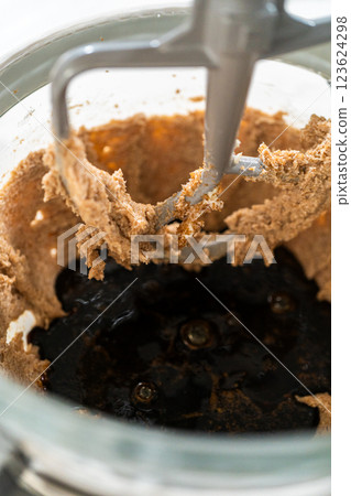 Close-up of molasses being added to the creamed butter and sugar mixture for Spiced Gingerbread Cookie Dough Perfect for Baking. The dark molasses contrasts with the light dough, creating a rich, dark 123624298