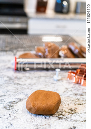 In a contemporary white kitchen, gingerbread cookie dough is skillfully rolled out, setting the stage for a delightful holiday treat. In a contemporary white kitchen, gingerbread cookie dough is skillfully rolled out, setting the stage for a delightful holiday treat. 123624300